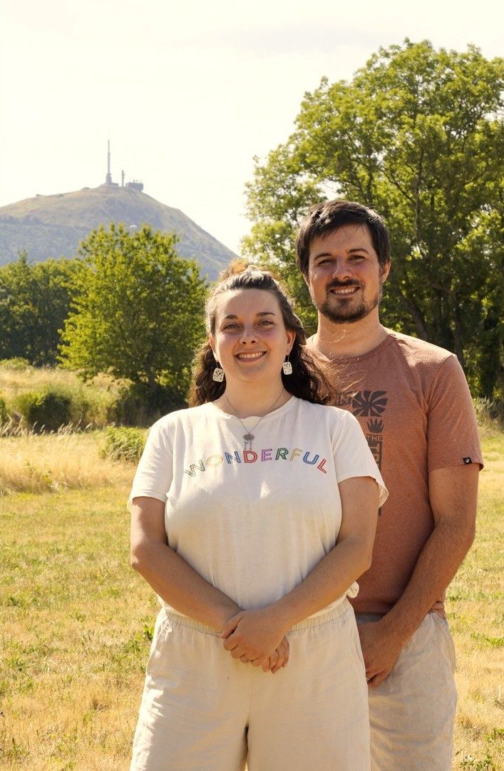 Laeticia et Alex debout dans un pré, le puy de Dôme derrière eux