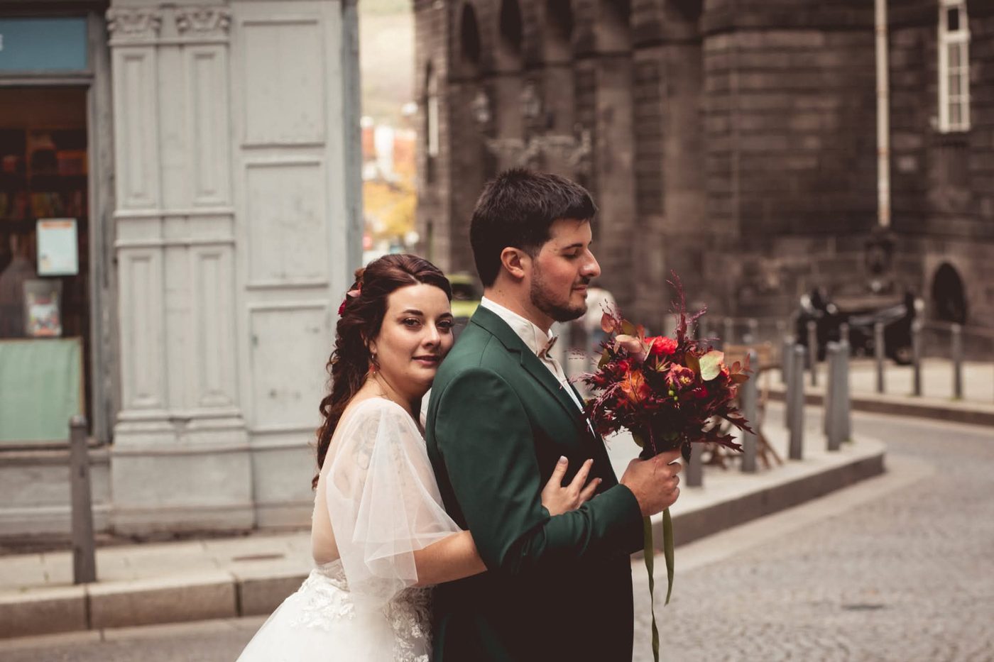 Laeticia et Alex le jour de leur mariage, dans une rue de Clermont-Ferrand, elle enlaçant son mari qui tient un bouquet aux tons rouges